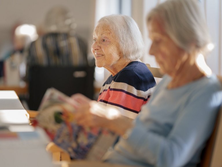 Frau liest ein Buch an einem Esstisch 